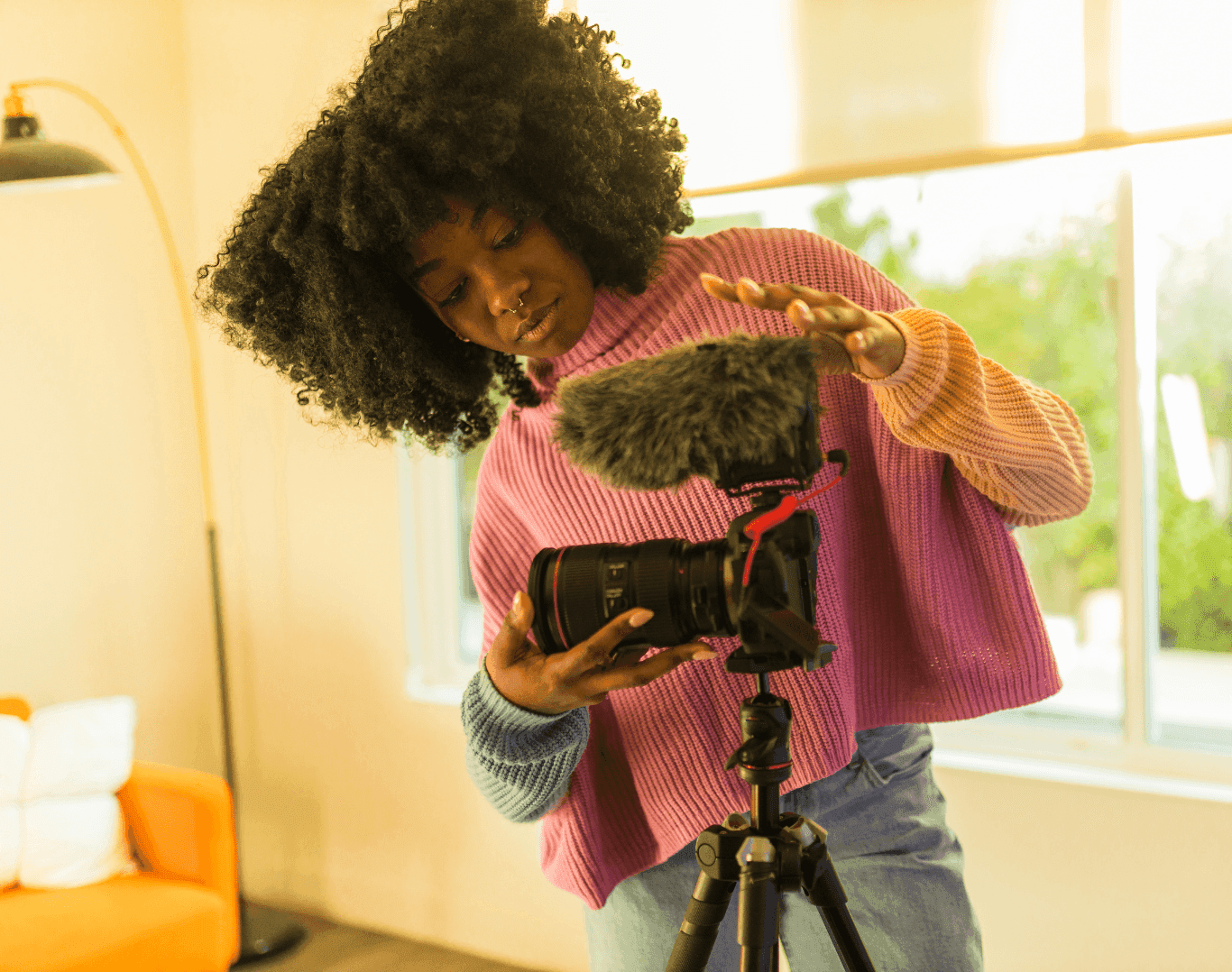 Creative woman adjusting a camera with a microphone indoors, preparing to film content for social media.