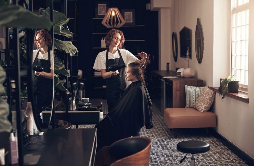 Hairstylist working with a client in a modern salon, representing the idea of setting clear goals for social media success.