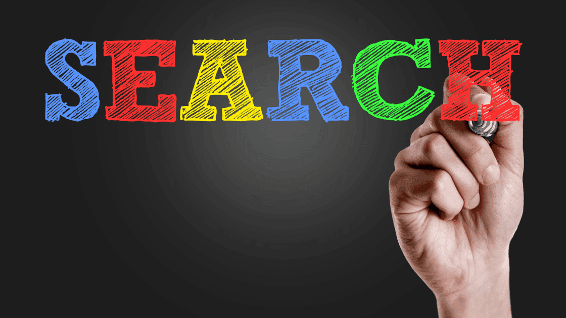 Hand writing the word "SEARCH" in colourful chalk-style letters on a black background, representing SEO and Google search visibility.